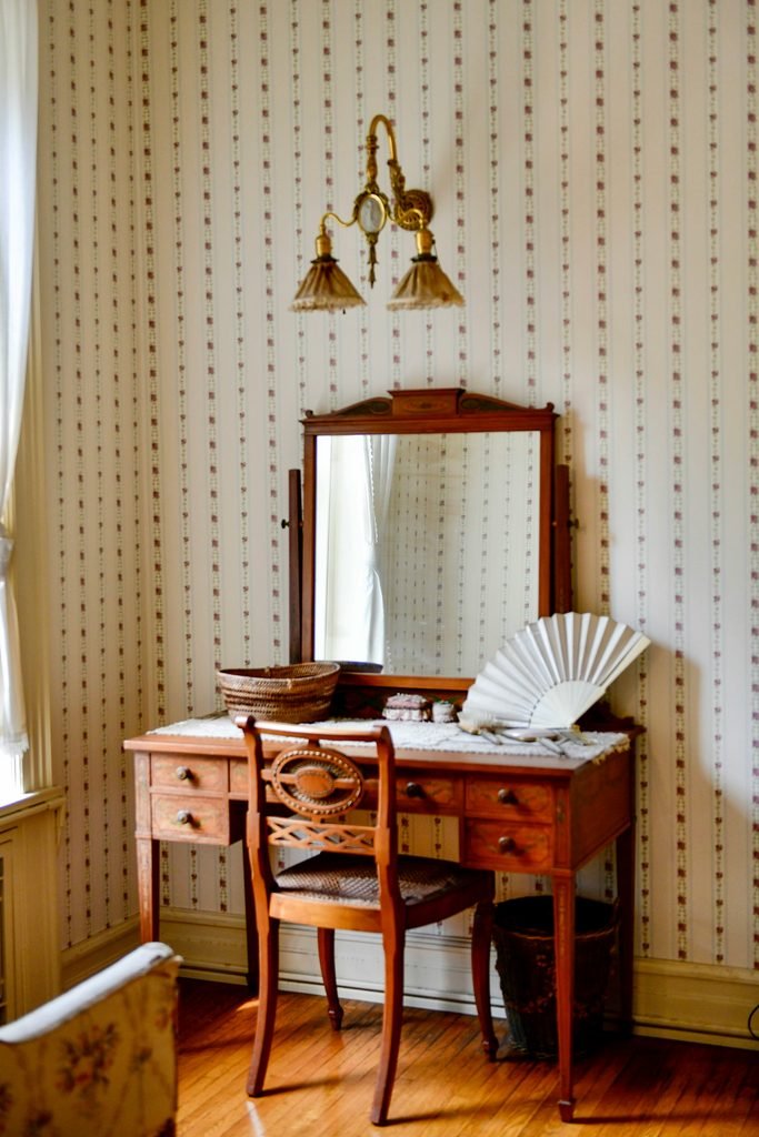 Elegant feminine vanity with a mirror, soft lighting, and beautifully styled decor