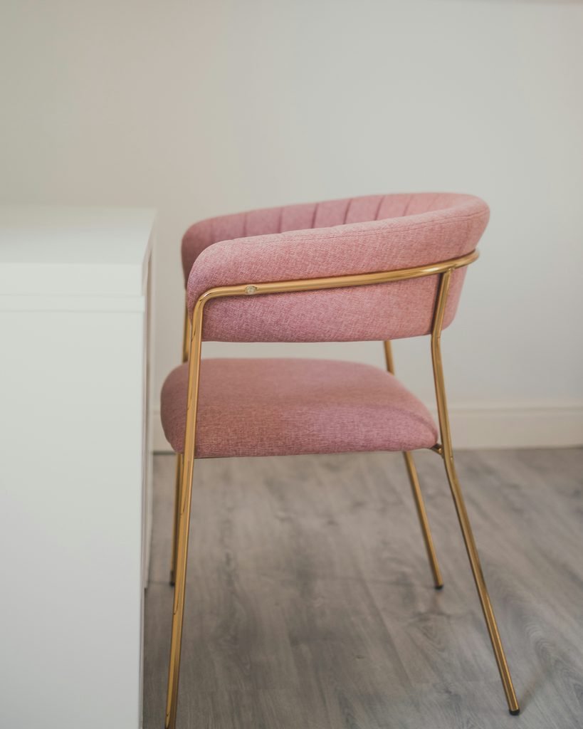 Pink upholstered vanity chair with a warm wooden frame