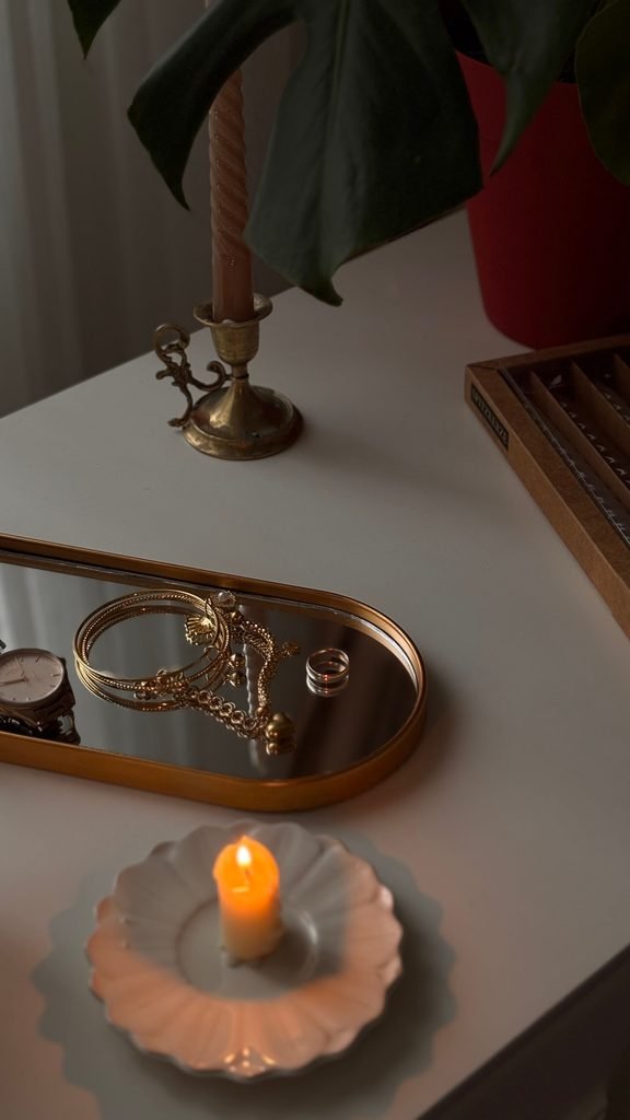 Feminine vanity styling with jewelry, candlelight, a ceramic dish, and elegant decor